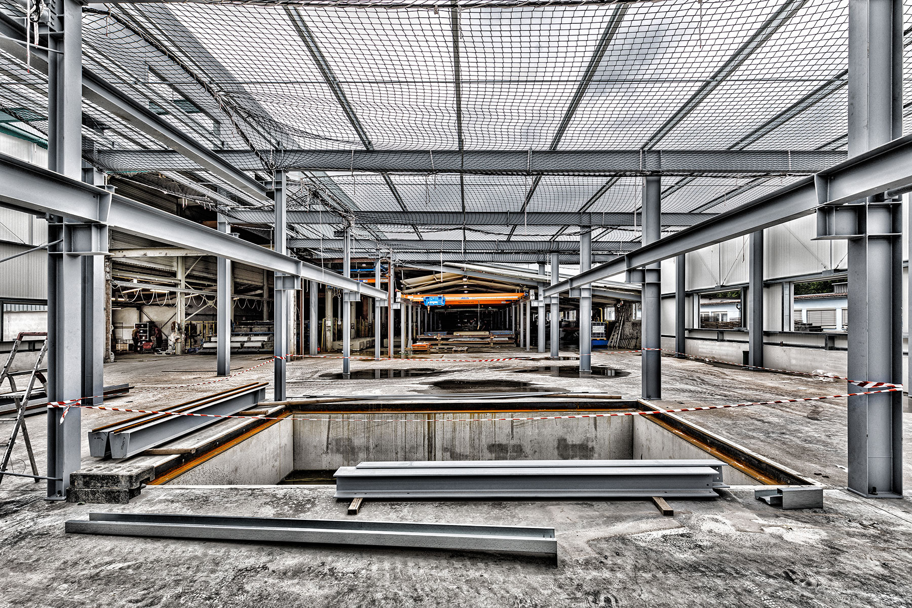 Aufbau der Stahlkonstruktion für eine Industriehalle mit Montagegrube an eine bestehende Produktionshalle.